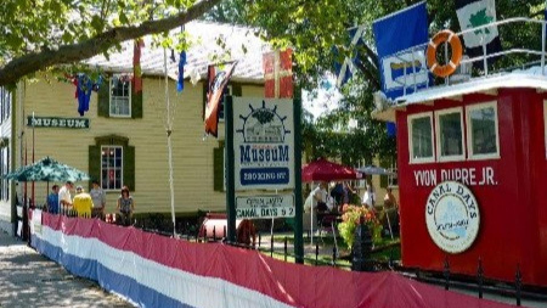 A maritime museum with colourful flags and a red boat display nearby.