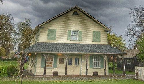 Two-story building with a porch under a cloudy sky.