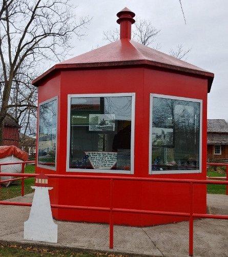 Red octagonal structure with large windows and surrounded by leafless trees.