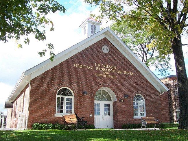 Brick building with arched windows, benches, and trees.