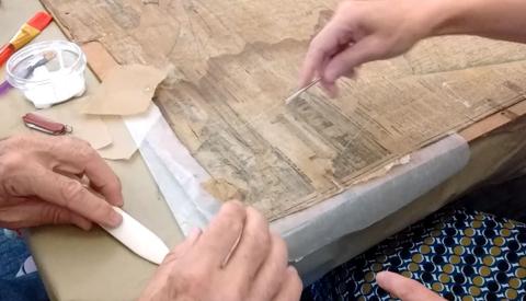 Restoration of an old newspaper with tools on a table.